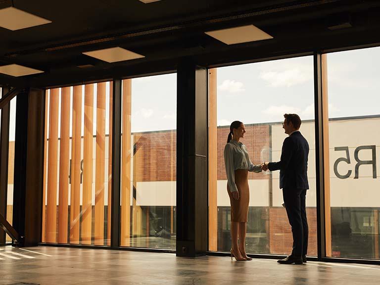 Two people shaking hands in office building (commercial real estate trends)